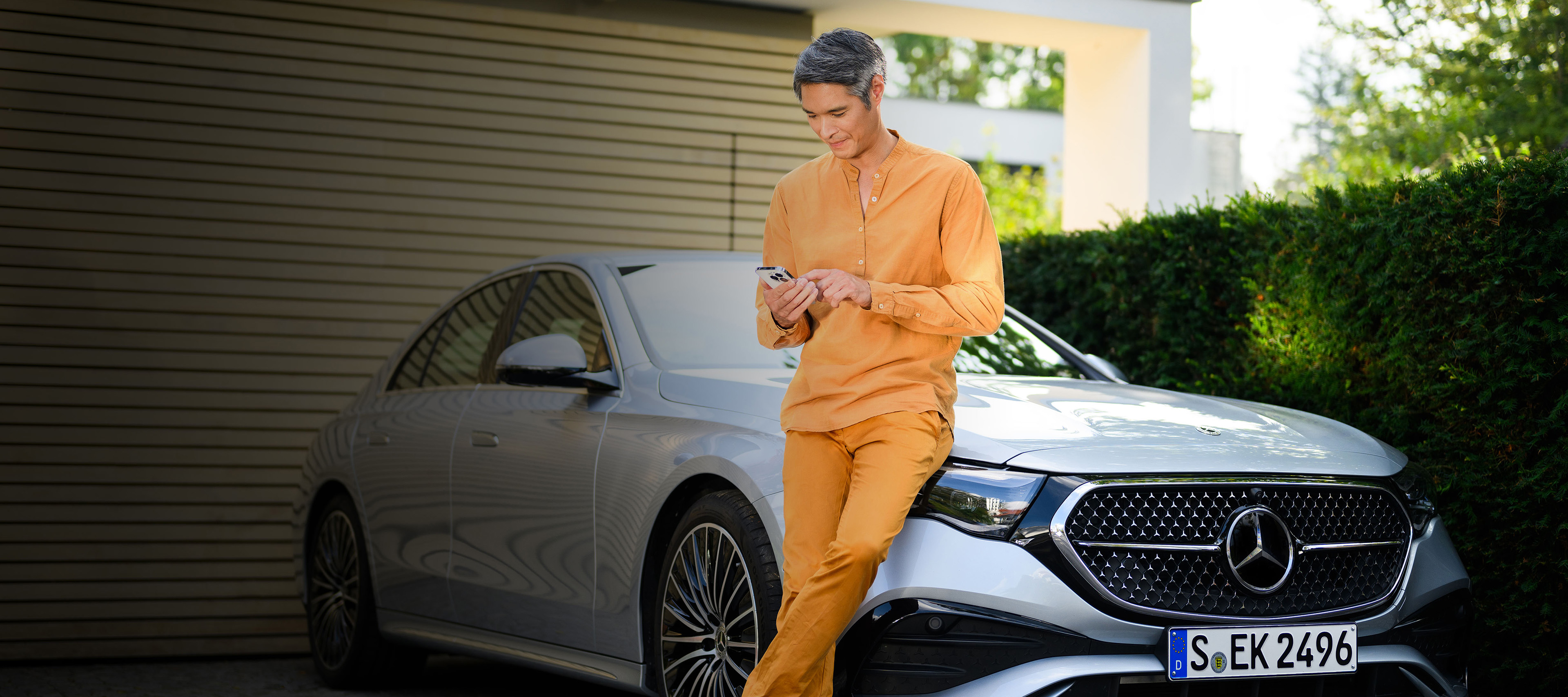 Standard Finance for your Mercedes-Benz A person leaning against a Mercedes-Benz vehicle, using a mobile device.