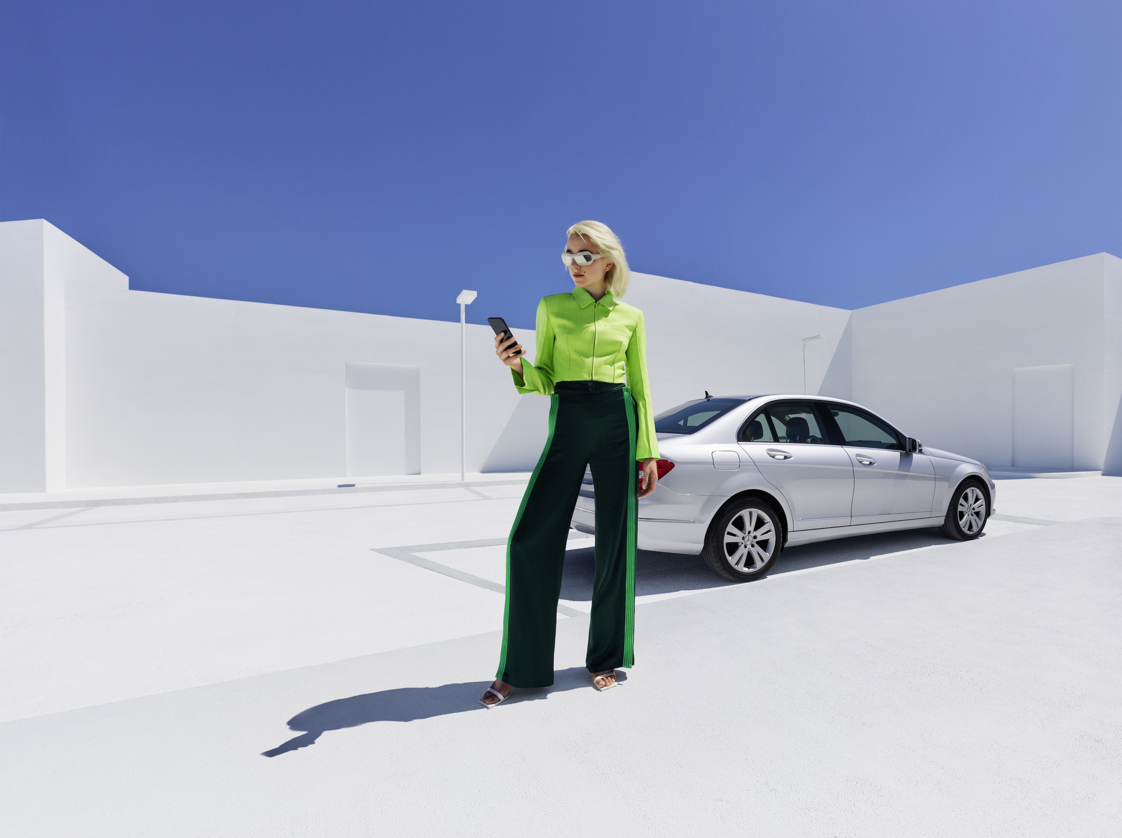 Mercedes-Benz adapter A woman in front of a Mercedes-Benz looking at her smartphone.