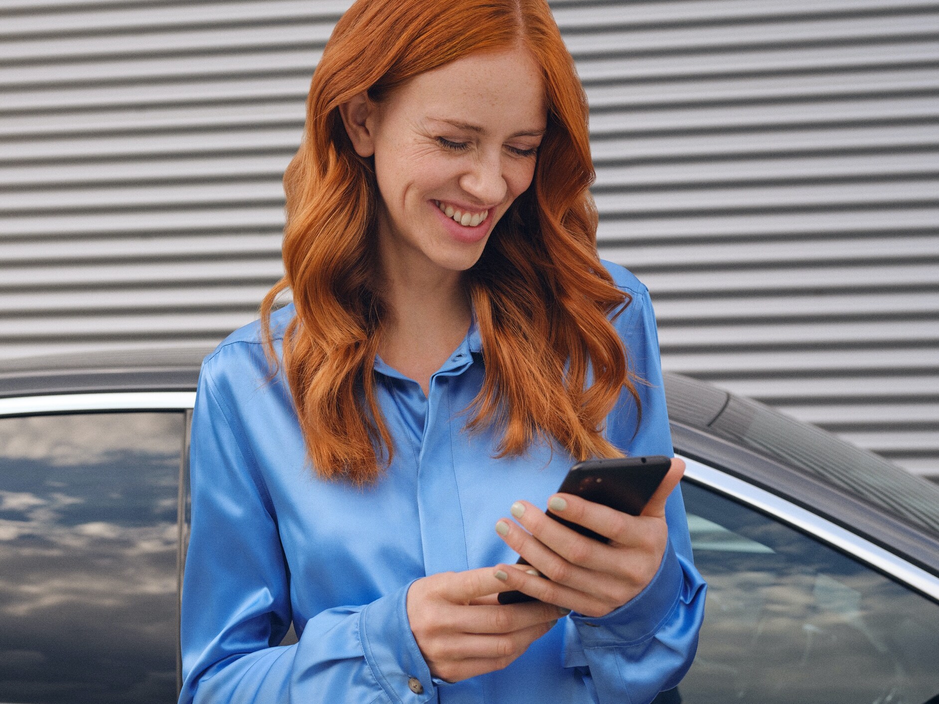 A woman connects to her Mercedes-Benz via the Mercedes me App on her smartphone.