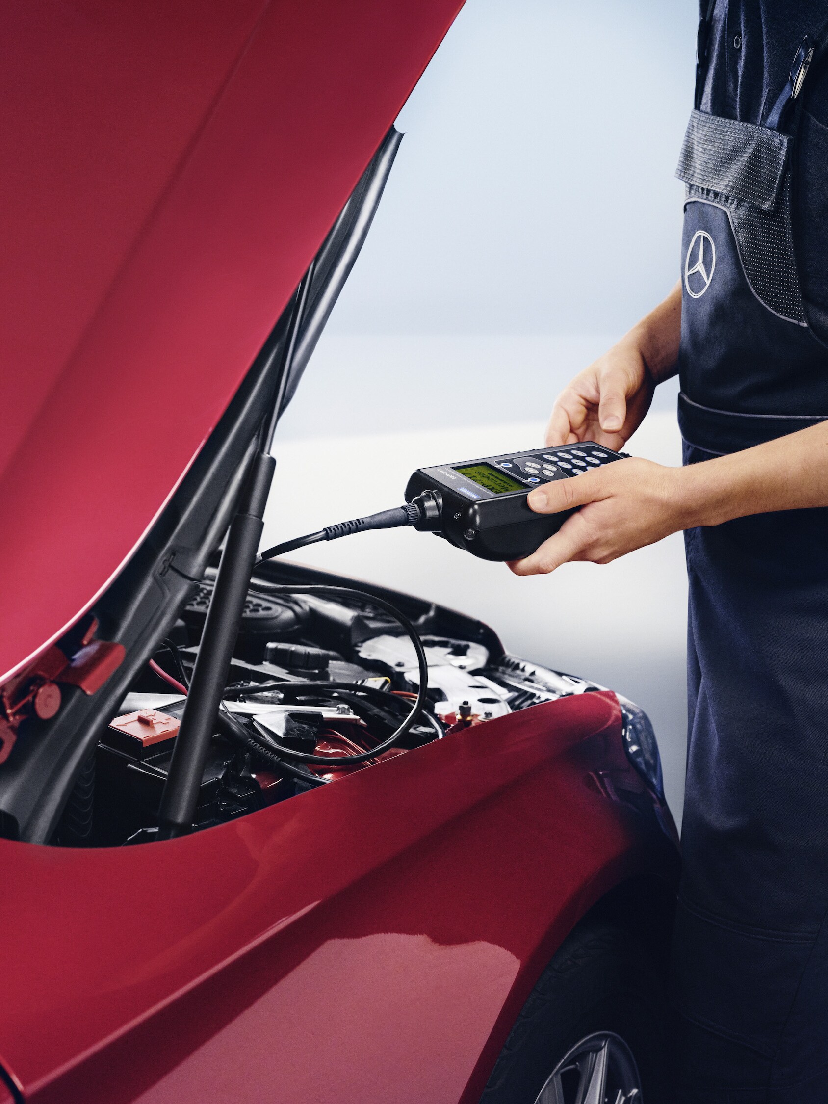 A Mercedes-Benz technician checks the vehicle's electrical system battery.