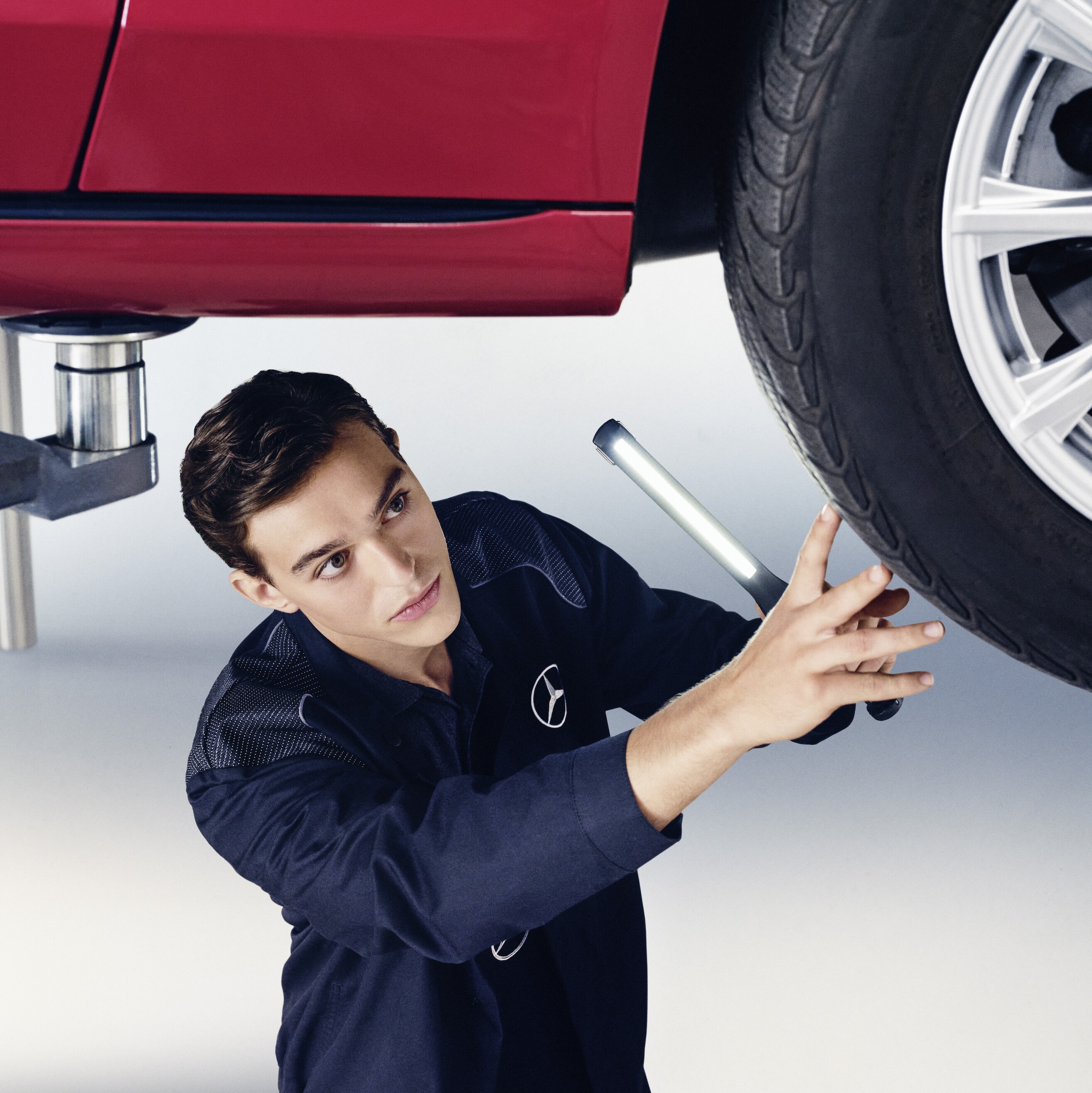 A Mercedes-Benz technician checks the underside of a vehicle.