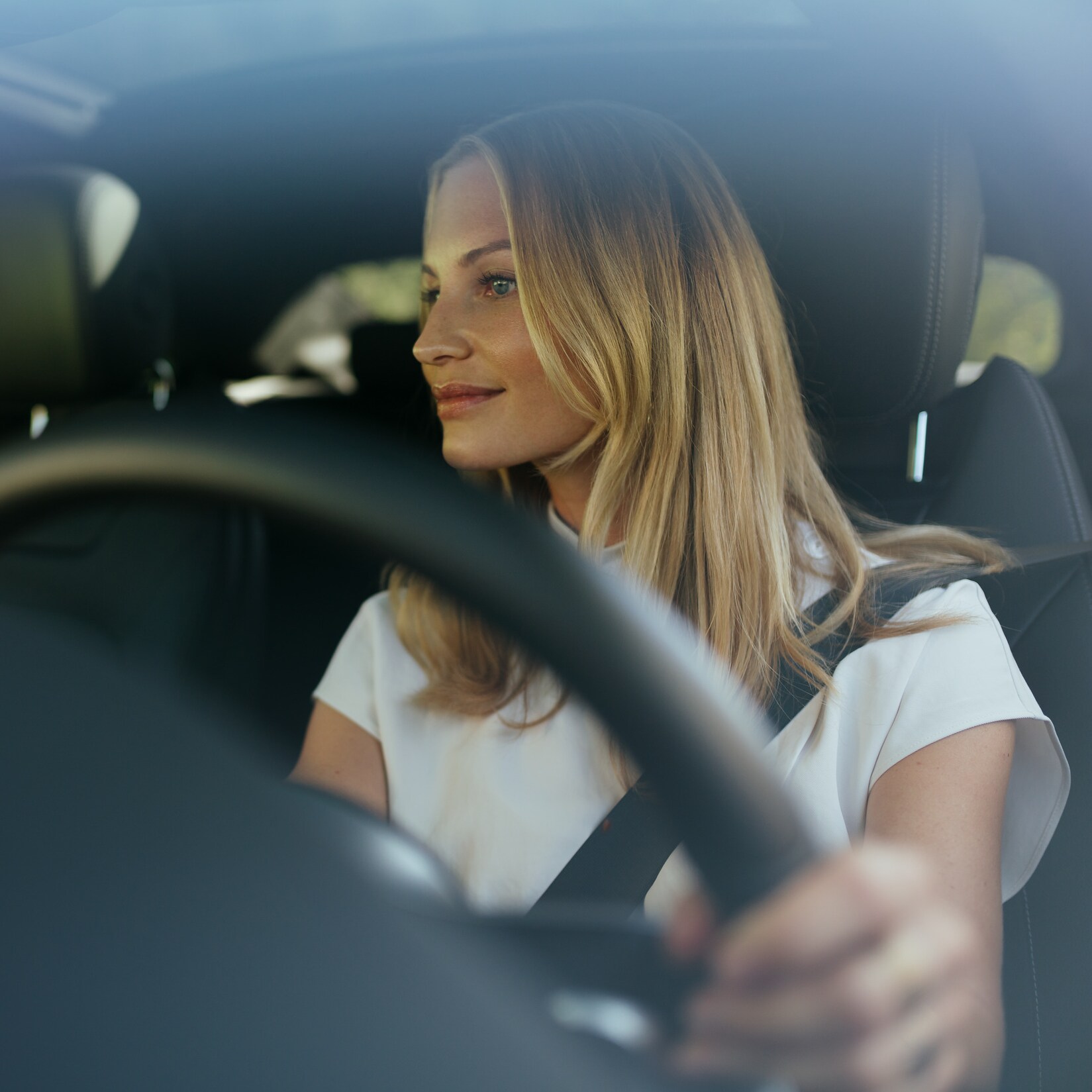 A relaxed woman at the wheel of her Mercedes.