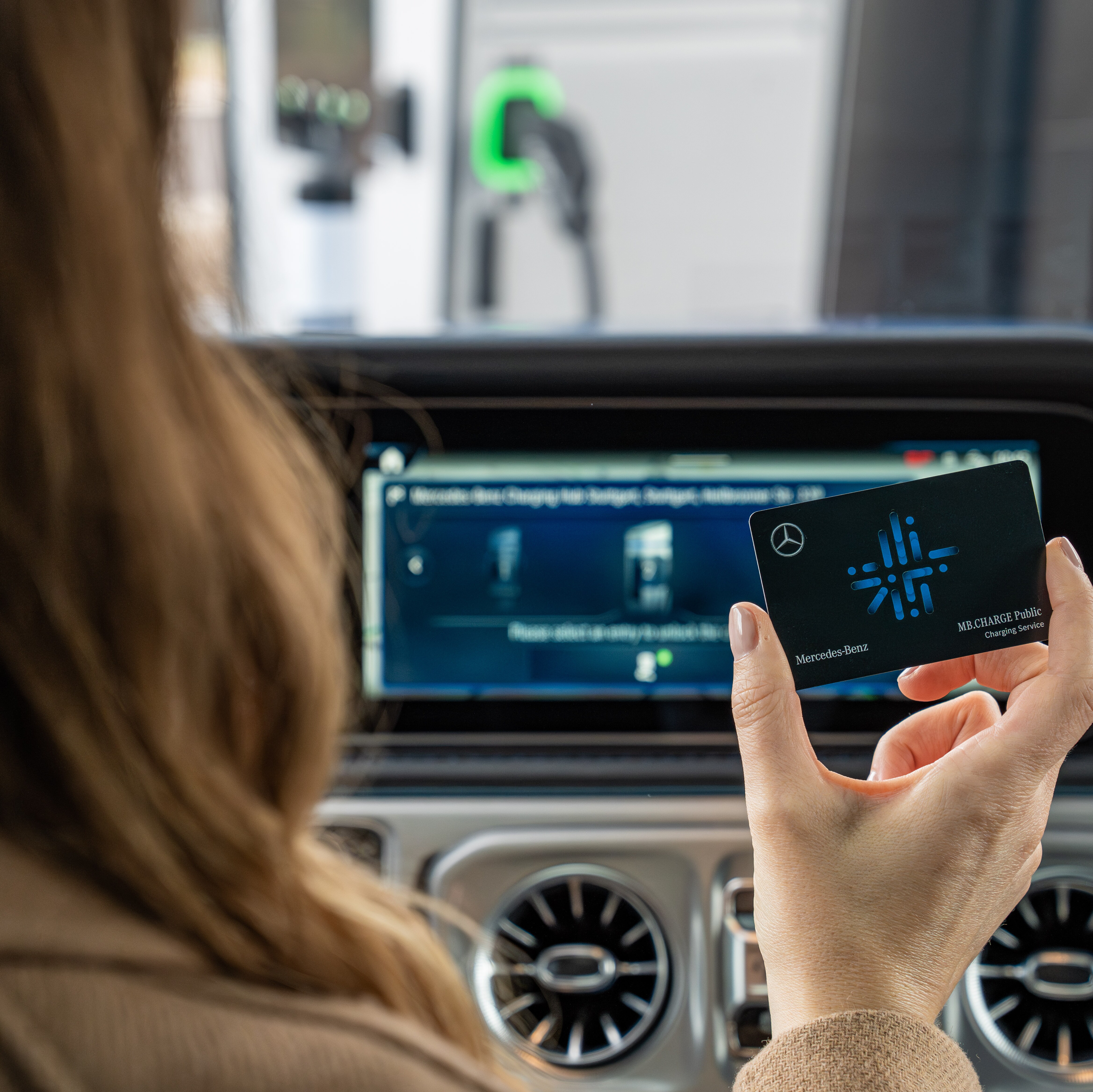 A person operating the navigation system from Mercedes-Benz, which also displays public charging station locations