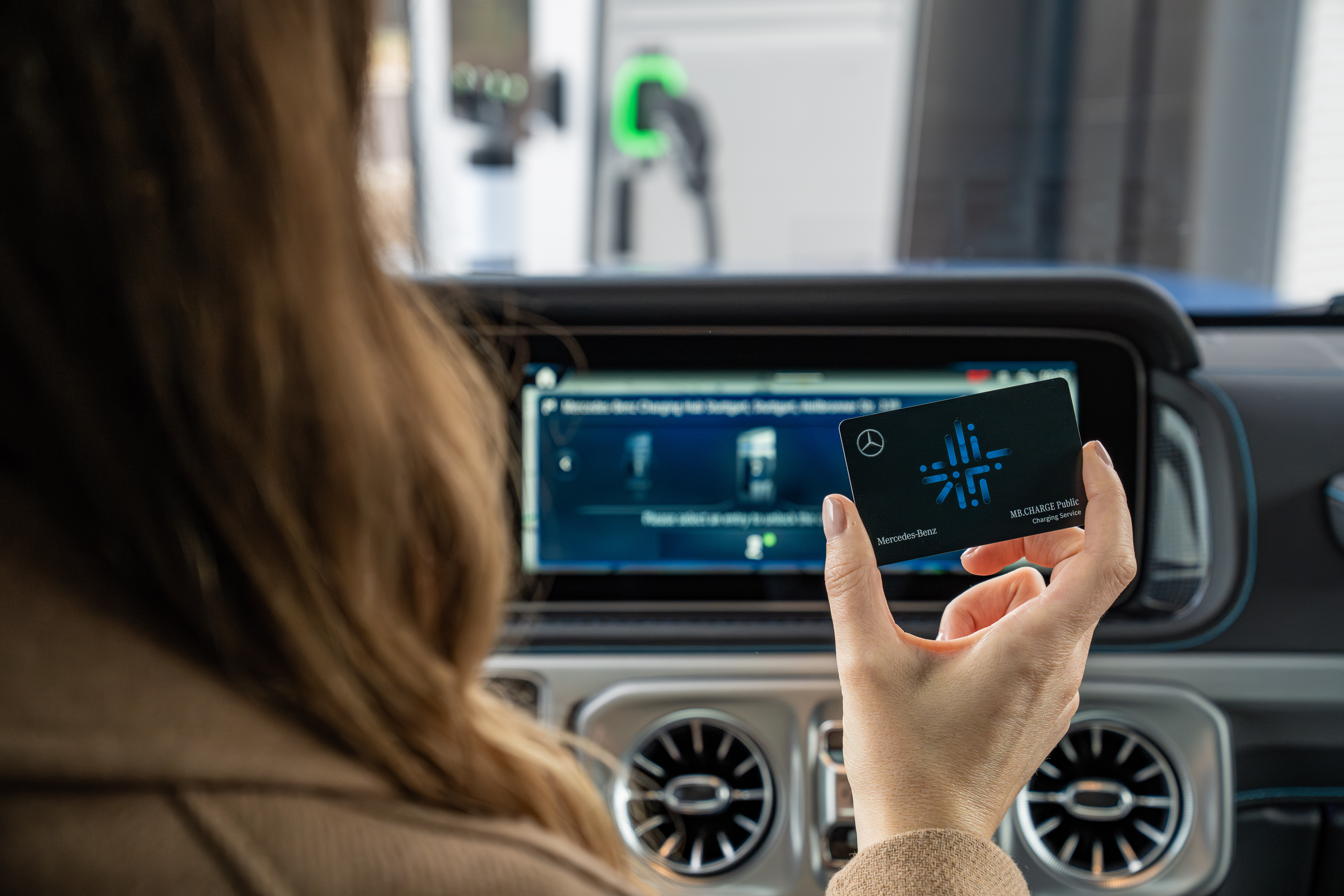 Mercedes-Benz Navigation including Mercedes me Charge A person operating the navigation system from Mercedes-Benz, which also displays public charging station locations